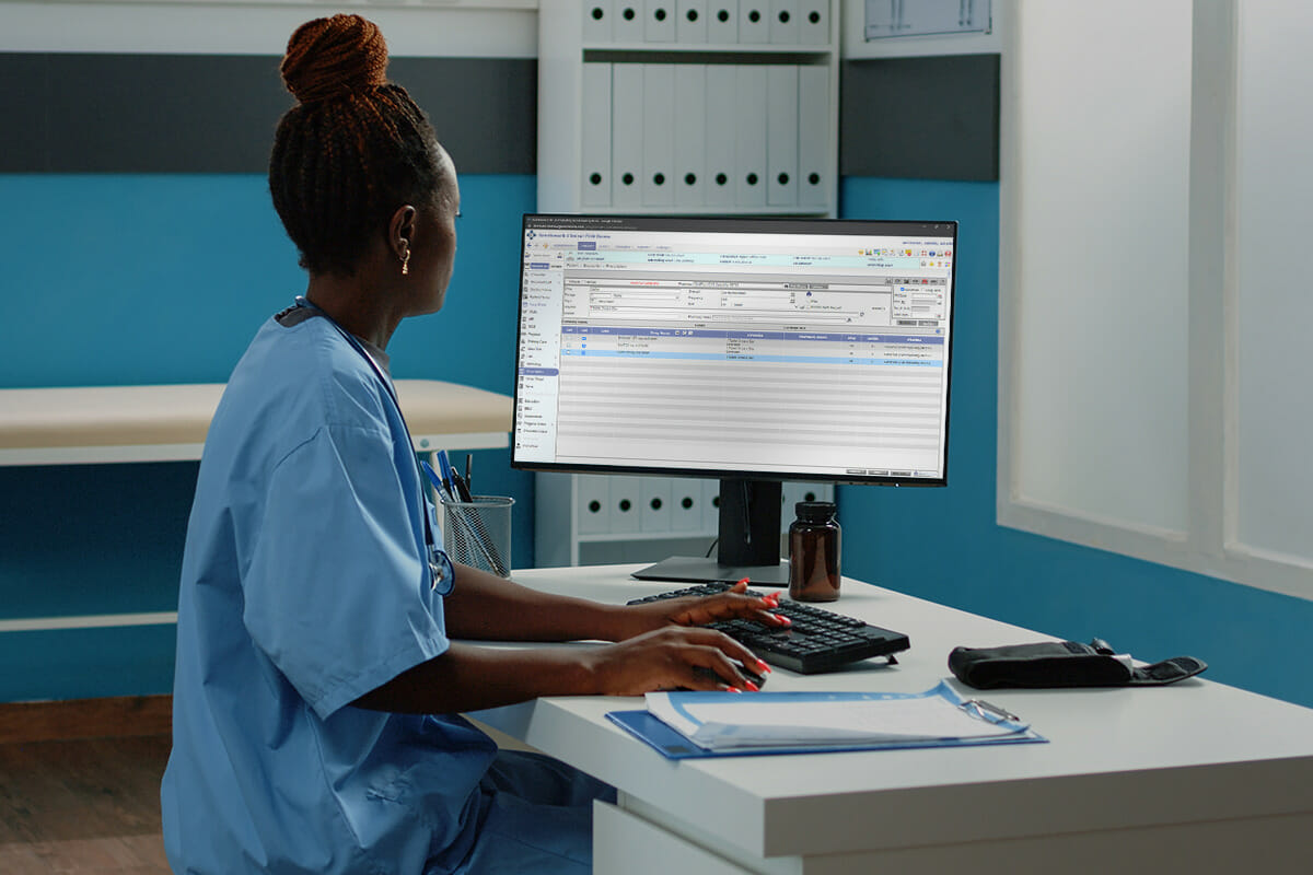 A woman uses a computer to view cloud-based EHRs.